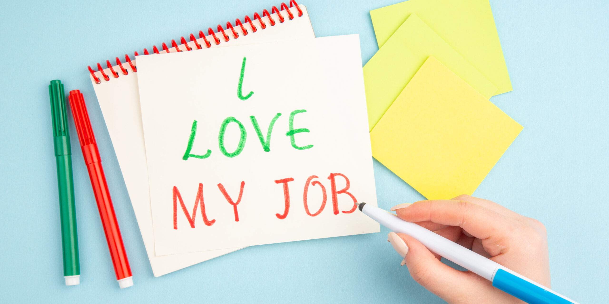 top-view-i-love-my-job-written-sticky-note-pen-female-hand-yellow-sticky-papers-markers-blue